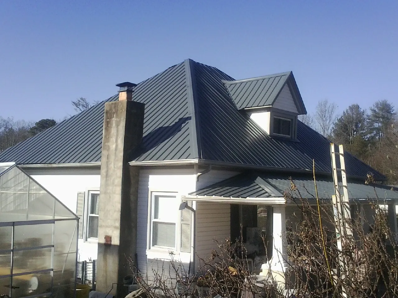 Dark blue standing seam metal roof on a white farmhouse with dormer — Slate & Tile Roof Repair by Roofing Brothers in Wheeler
