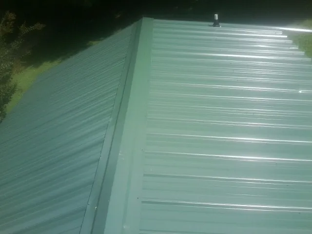 New green metal panels meeting at the ridge of a roof — Flat Roof Repair work by our crew in Wheeler