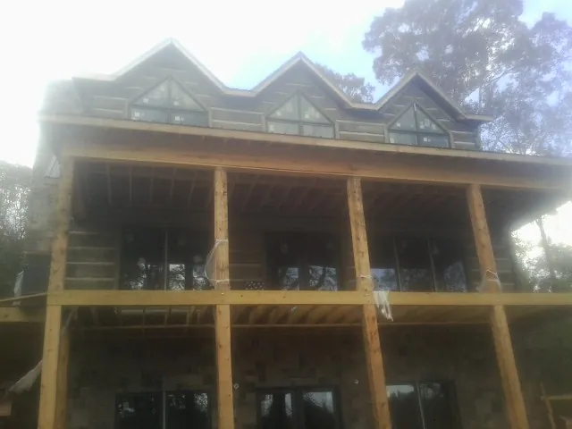 Dormers and porch framing on a large log home under construction — Roof Coating work by our crew in Wheeler