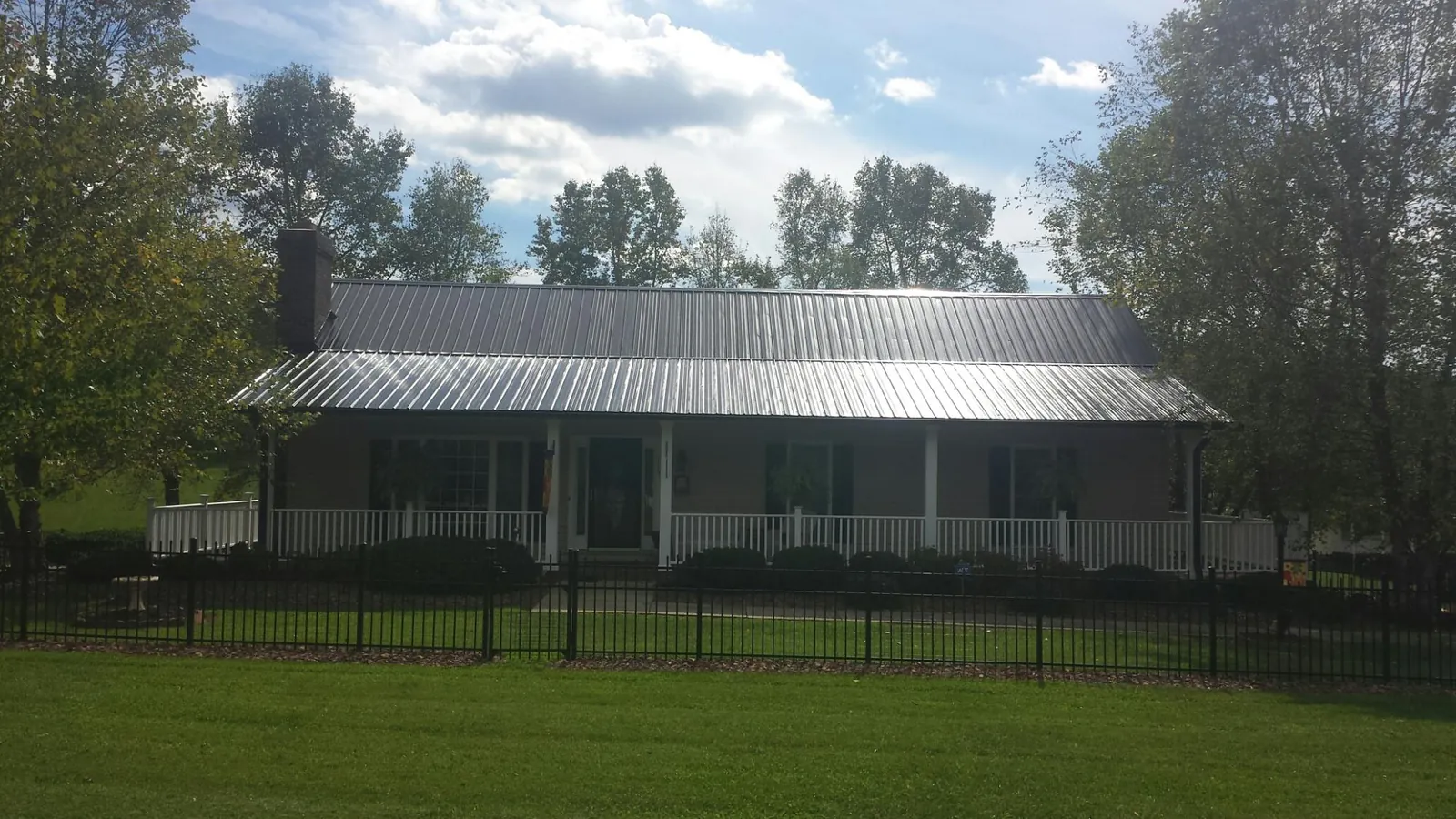Gray metal roof on a brick ranch with a full width front porch — Gutter Guard Installation work by our crew in Wheeler