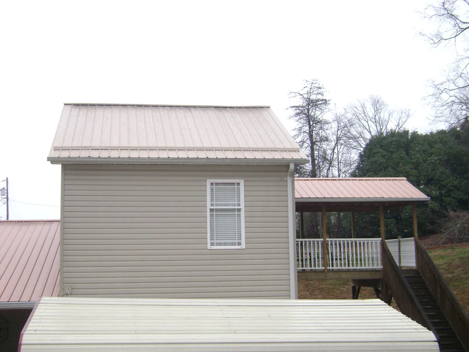 Tan metal roofs on a two story addition and attached porch, from a Roof Replacement job in Wheeler