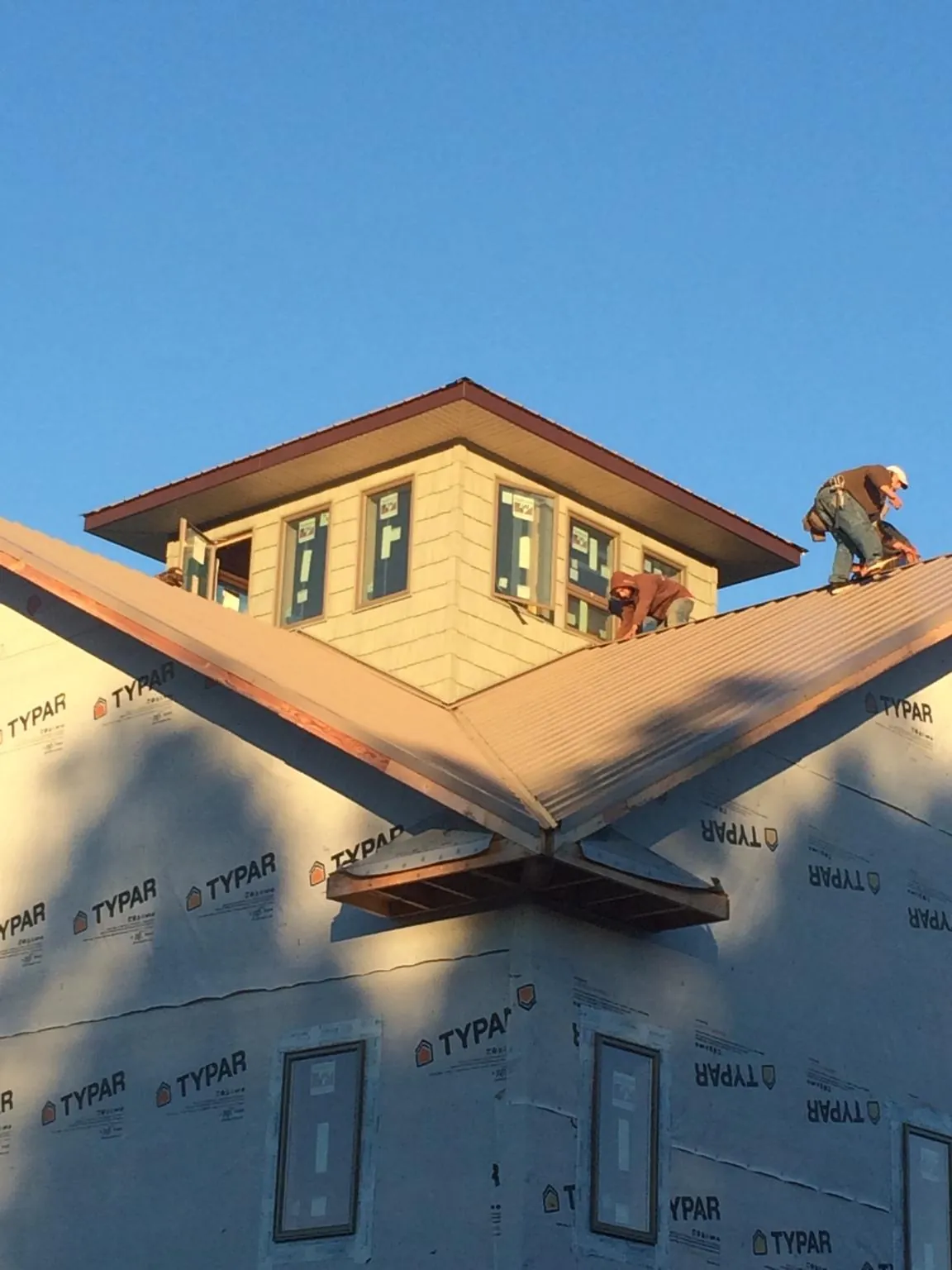 Roofers working around a rooftop cupola on a new metal roof at sunset — Roof Waterproofing in Wheeler by Roofing Brothers